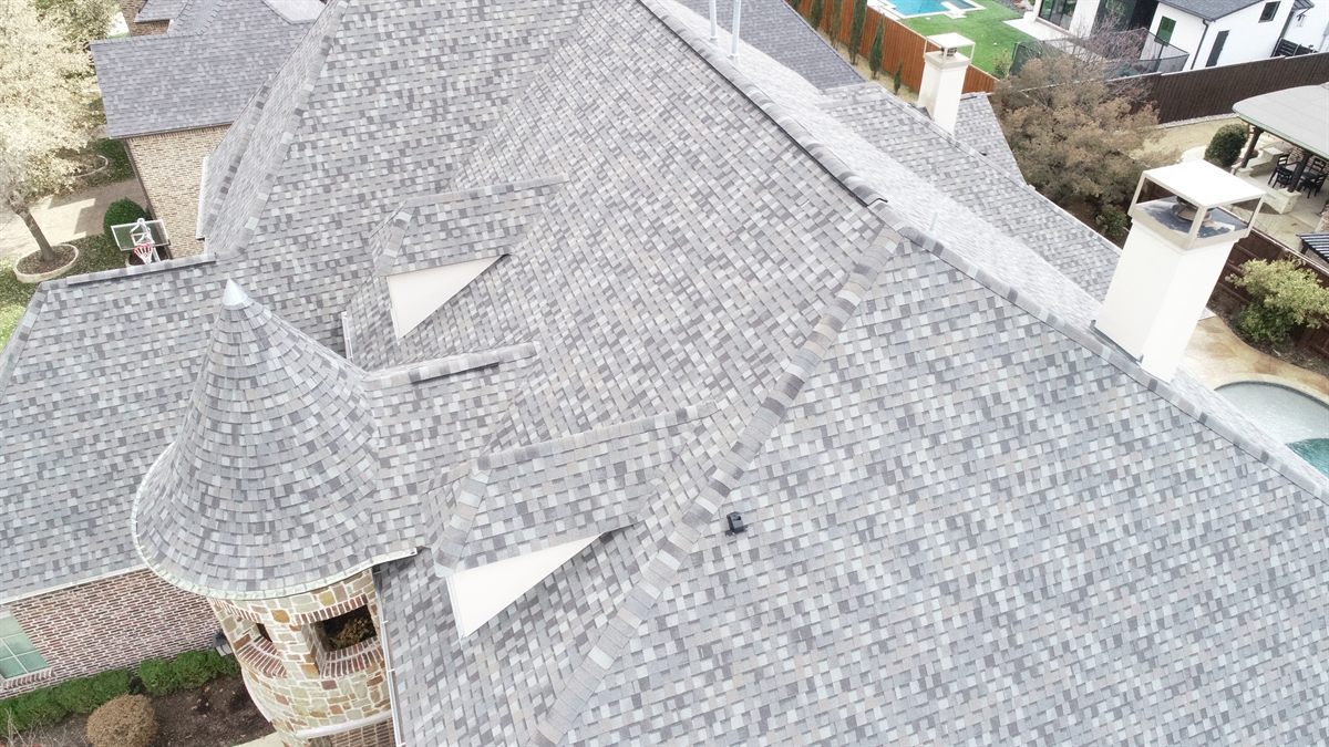 Aerial view of a large luxury home with turret and pool in McKinney featuring a newly installed designer architectural shingle roof